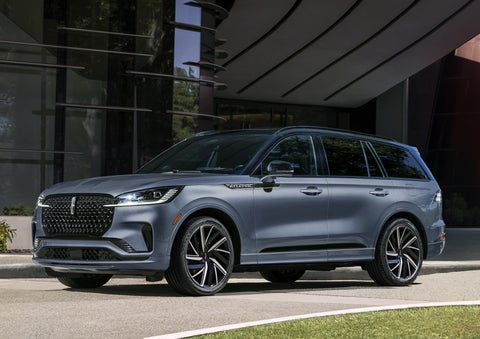 A gray 2025 Lincoln Aviator® SUV is parked outside a modern building showcasing the driver’s side of the vehicle. | Palmetto Lincoln in Charleston SC