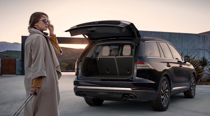 A woman approaches a 2026 Lincoln Aviator® SUV with its rear liftgate open. | Palmetto Lincoln in Charleston SC