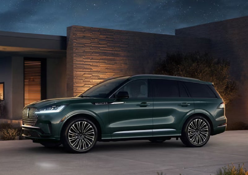 A green 2027 Lincoln Aviator® SUV is parked outside a contemporary home. | Palmetto Lincoln in Charleston SC