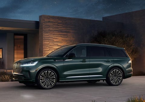 A green 2027 Lincoln Aviator® SUV is parked outside a contemporary home. | Palmetto Lincoln in Charleston SC