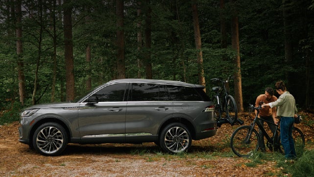 A father and son load e-bikes on a bike rack attached to a 2027 Lincoln Aviator® SUV. | Palmetto Lincoln in Charleston SC
