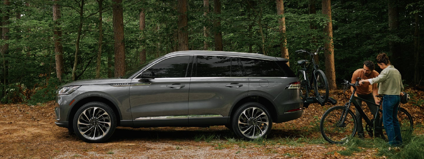 A father and son load e-bikes on a bike rack attached to a 2027 Lincoln Aviator® SUV. | Palmetto Lincoln in Charleston SC